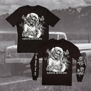 May include: A black short-sleeved t-shirt and a black long-sleeved shirt, both featuring a white graphic of a woman with blonde hair, butterflies, and flowers. The text "ANGELS NEVER DIE" is printed below, and the long-sleeved shirt includes "I will always love you" on the sleeve.