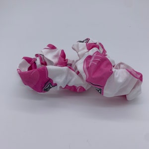May include: White and pink fabric hair scrunchie with a pink heart pattern.