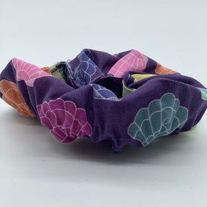May include: Purple fabric scrunchie with a colorful seashell pattern.