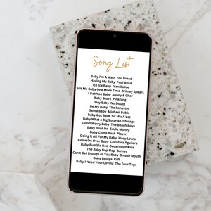 May include: A smartphone screen displaying a list of songs titled "Song List". The list includes songs about babies, such as "Baby I'm A Want You Bread", "Having My Baby", "Ice Ice Baby", "Hit Me Baby One More Time", and "I Got You Babe".