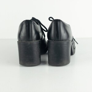 May include: A pair of black leather platform shoes with lace-up closures. The shoes have a chunky heel and a rounded toe.