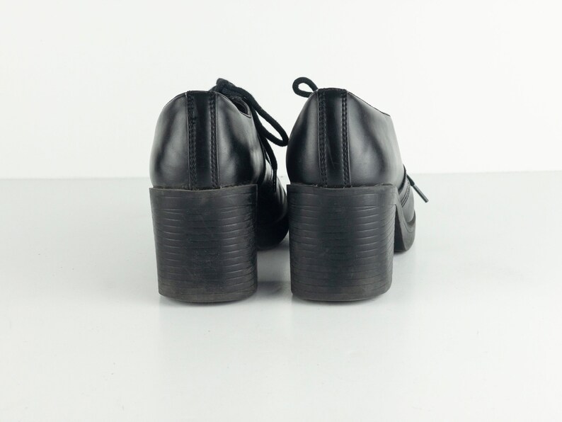 May include: A pair of black leather platform shoes with lace-up closures. The shoes have a chunky heel and a rounded toe.