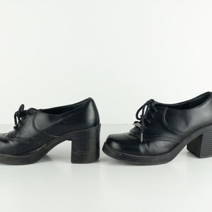 May include: A pair of black leather platform shoes with lace-up closures. The shoes have a chunky heel and a rounded toe.