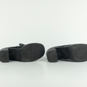 May include: A pair of black leather platform shoes with a chunky heel. The shoes have a lace-up front and a textured sole.