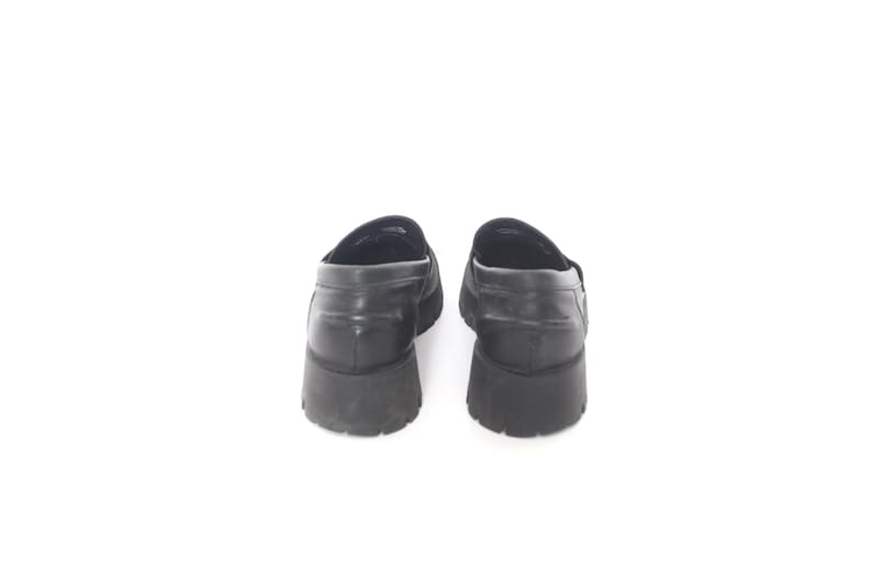 May include: A pair of black leather loafers with a chunky rubber sole.