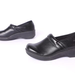 Può includere: Un paio di scarpe nere in pelle con un tacco basso. Le scarpe hanno un design semplice e sono realizzate in un materiale comodo.