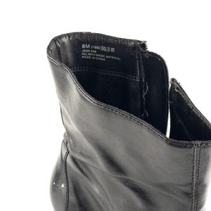 May include: Black leather ankle boots with a zipper on the side. The inside of the boot shows the label with the text "8M 27949  MADE IN CHINA  JEAN 566  ALL MAN MADE MATERIAL".
