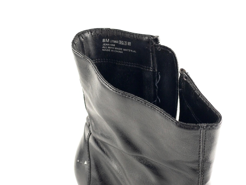 May include: Black leather ankle boots with a zipper on the side. The inside of the boot shows the label with the text "8M 27949  MADE IN CHINA  JEAN 566  ALL MAN MADE MATERIAL".