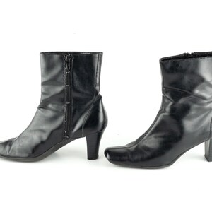 May include: A pair of black leather ankle boots with a pointed toe and a block heel. The boots have a zipper on the inside of each boot.