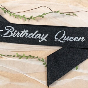 May include: Black sparkly sash with silver glitter lettering that reads "Birthday Queen".