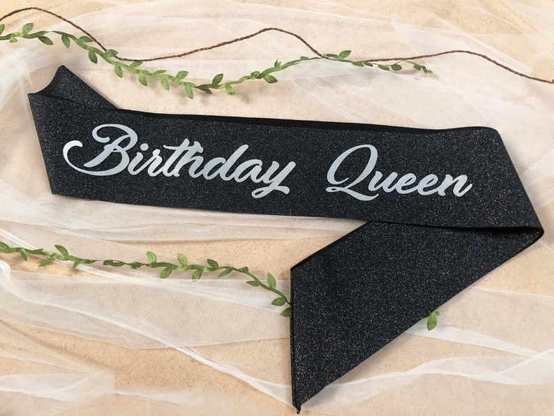 May include: Black sparkly sash with silver glitter lettering that reads "Birthday Queen".