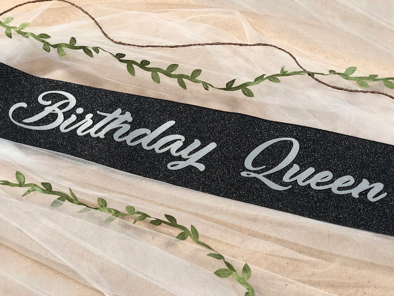 May include: Black sparkly sash with silver glitter lettering that reads "Birthday Queen".