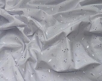May include: White cotton fabric with a delicate embroidered floral pattern. The embroidery is in a lighter shade of white, creating a subtle contrast against the fabric.