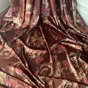 K&ouml;nnte beinhalten: Brauner Satin-Stoff mit einem Blumendruck mit goldenen und roten Rosen. Der Stoff f&uuml;hlt sich weich und luxuri&ouml;s an.