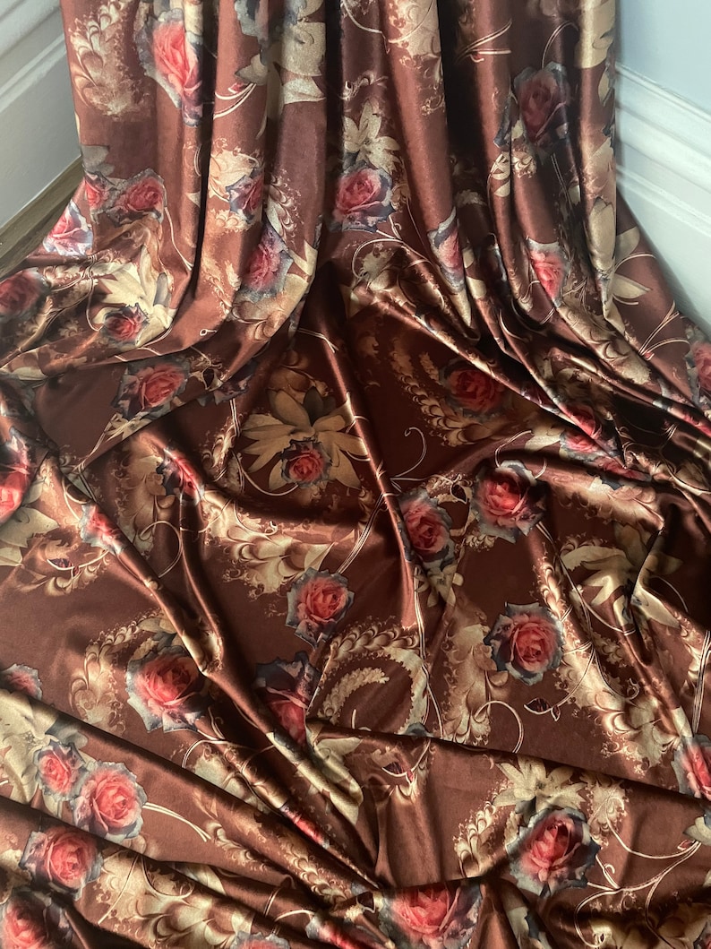 K&ouml;nnte beinhalten: Brauner Satin-Stoff mit einem Blumendruck mit goldenen und roten Rosen. Der Stoff f&uuml;hlt sich weich und luxuri&ouml;s an.