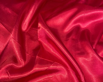 May include: Close-up of a smooth, red satin fabric with soft folds and wrinkles.