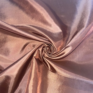Könnte beinhalten: Nahaufnahme eines glatten, seidenartigen Stoffes in einer satten, warmen braunen Farbe. Der Stoff ist drapiert und gefaltet und erzeugt weiche, fließende Linien und ein luxuriöses Gefühl.