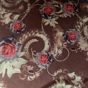 K&ouml;nnte beinhalten: Ein brauner Stoff mit einem floralen Muster mit rosa Rosen und goldenen Wirbeln. Der Stoff hat eine weiche, strukturierte Oberfl&auml;che.