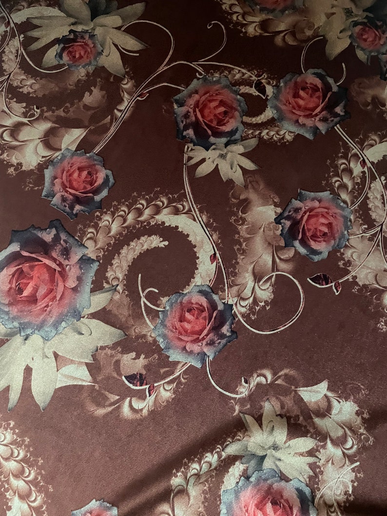 K&ouml;nnte beinhalten: Ein brauner Stoff mit einem floralen Muster mit rosa Rosen und goldenen Wirbeln. Der Stoff hat eine weiche, strukturierte Oberfl&auml;che.