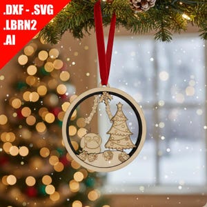 May include: Wooden Christmas ornament with a circular frame, featuring a laser-cut design of a Christmas tree, a character, and decorative elements. The ornament hangs from a red ribbon. The text '.DXF .SVG .LBRN2 .AI' is in the upper left corner.