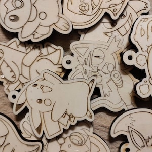 May include: A collection of unfinished wooden cutouts featuring various cartoon character designs. Each cutout has a small hole for hanging and is made of light-colored wood with dark brown etched outlines.