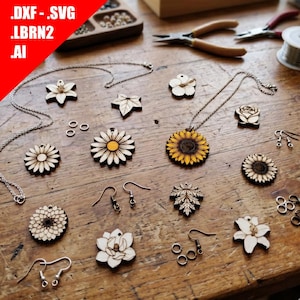 Può includere: Ciondoli e orecchini floreali in legno con vari disegni, tra cui girasoli e margherite, sono esposti su una superficie di legno. L'immagine mostra anche strumenti per la creazione di gioielli e il testo '.DXF .SVG .LBRN2 .AI' in alto a sinistra.