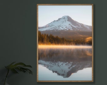 May include: A framed photograph of a snow-capped mountain reflected in a still lake with a misty morning fog. The mountain is surrounded by a forest of evergreen trees.