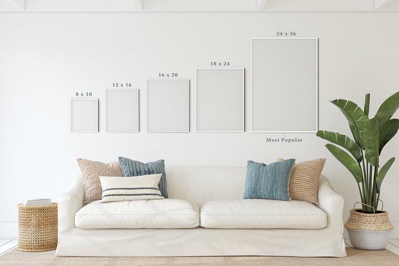 May include: A white sofa with pillows in various shades of blue and brown, a small side table with a woven basket, and a large potted plant. The wall behind the sofa has five white frames with different dimensions, labeled with their size in inches. The largest frame is labeled "24 x 36" and "Most Popular".