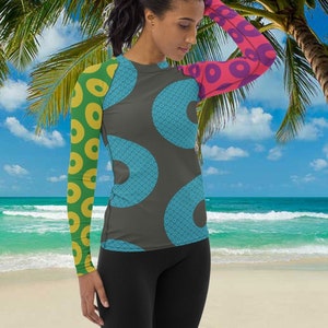 May include: A long-sleeved shirt with a geometric pattern of circles in shades of blue, green, yellow, pink, and purple. The shirt is made of a stretchy, comfortable material and is perfect for water sports or lounging on the beach.