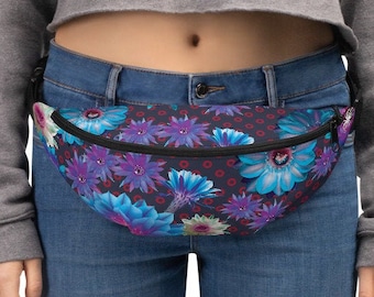 May include: A black fanny pack with a floral print featuring blue, purple, and white flowers on a dark background. The fanny pack has a black adjustable strap.