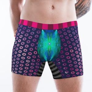 May include: Boxer briefs with a navy blue background and pink circle pattern. The waistband is pink and burgundy striped. The front panel features a teal and blue abstract design, and the leg openings have a black and gray striped pattern.