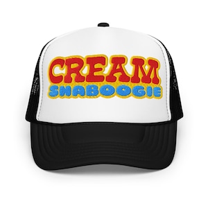 Puede incluir: Gorra de camionero en blanco y negro con la palabra "CREAM" en rojo, contorneada en amarillo, encima de "SHABOOGIE" en azul. La gorra tiene un panel frontal blanco y una parte trasera de malla negra.
