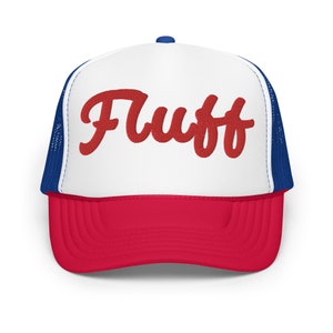 May include: A white and red trucker hat with a blue mesh back. The hat has the word "Fluff" embroidered in red on the front.