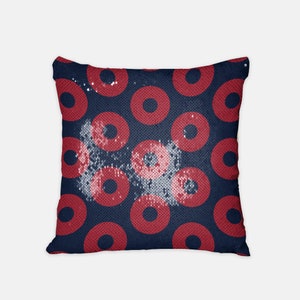May include: A blue and red sequin pillow with a donut pattern. The donuts are red with a white center.