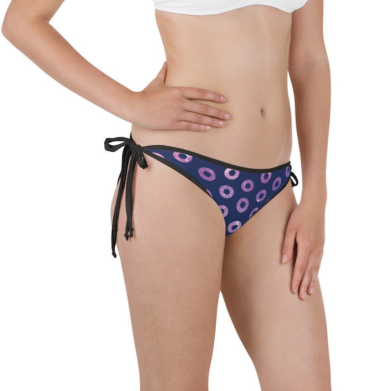 Op de afbeelding: Donkerblauwe bikini onderkant met een roze en wit donut patroon. De bikini onderkant heeft zwarte banden aan elke kant.