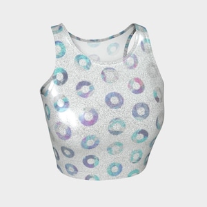 May include: A white crop top with a pattern of iridescent circles in shades of blue, purple, and teal. The top has a shiny, glittery texture and a racerback design.