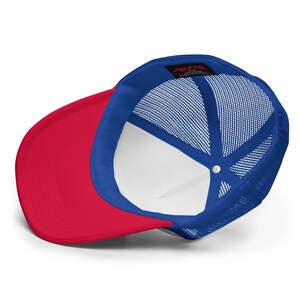 May include: Red and blue trucker hat with a mesh back. The hat has a white interior and a small black label with the text "OTTO" on the back.