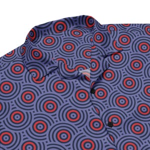 May include: A button-down shirt with a repeating pattern of concentric circles in red, black, and purple. The shirt has a collar and black buttons. The fabric has a silky appearance.