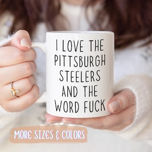 White ceramic mug with the text "I LOVE THE PITTSBURGH STEELERS AND THE WORD FUCK" in black.