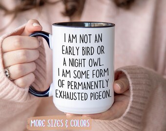 Può includere: Tazza in ceramica bianca con interno e manico neri, con la scritta "I AM NOT AN EARLY BIRD OR A NIGHT OWL. I AM SOME FORM OF PERMANENTLY EXHAUSTED PIGEON." La tazza ha anche la scritta "MORE SIZES & COLORS".