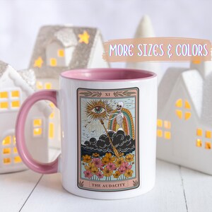 White ceramic mug with a pink interior and handle, featuring a tarot card design. The card depicts a skeleton, rainbow, and eye, with the text "THE AUDACITY". Gift for him. Gift for her. Birthday gift. Christmas present. 11oz and 15oz, several colors. Unique custom made coffee mug. Best friend mugs. Coffee lover. Secret santa. Coworker gift exchange. Stocking stuffer. White elephant. Novelty cup Dishwasher safe & microwave safe