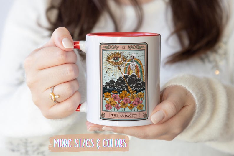 White ceramic mug with a red interior and handle. The mug features a tarot card design with a skeleton, rainbow, and flowers. The text "THE AUDACITY" is at the bottom of the card. Gift for him. Gift for her. Birthday gift. Christmas present. 11oz and 15oz, several colors. Unique custom made coffee mug. Best friend mugs. Coffee lover. Secret santa. Coworker gift exchange. Stocking stuffer. White elephant. Novelty cup Dishwasher safe & microwave safe