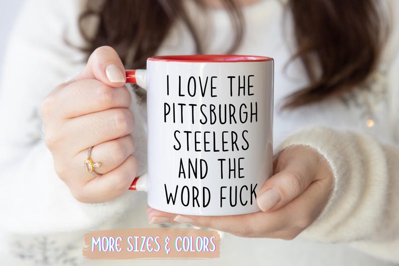 White ceramic mug with a red interior and handle. The mug features the text "I LOVE THE PITTSBURGH STEELERS AND THE WORD FUCK" in black.