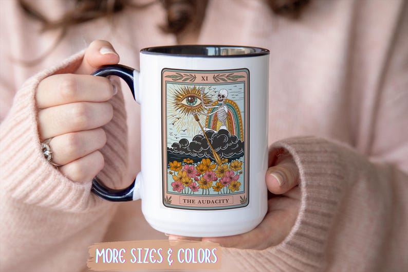 White ceramic mug with a black handle and rim, featuring a tarot card design. The card depicts an eye, skeleton, and rainbow, with the text "THE AUDACITY". Gift for him. Gift for her. Birthday gift. Christmas present. 11oz and 15oz, several colors. Unique custom made coffee mug. Best friend mugs. Coffee lover. Secret santa. Coworker gift exchange. Stocking stuffer. White elephant. Novelty cup Dishwasher safe & microwave safe