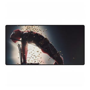 May include: A rectangular desk mat featuring a dynamic image of Deadpool, leaning back with bullets flying around him. The mat has a black border and a dark background with a bright light.