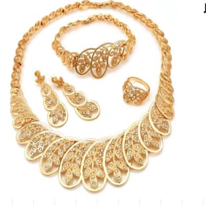 Puede incluir: Un juego de joyas de tono dorado con un collar, pulsera, pendientes y anillo. El juego presenta un delicado diseño de hojas con brillantes transparentes.