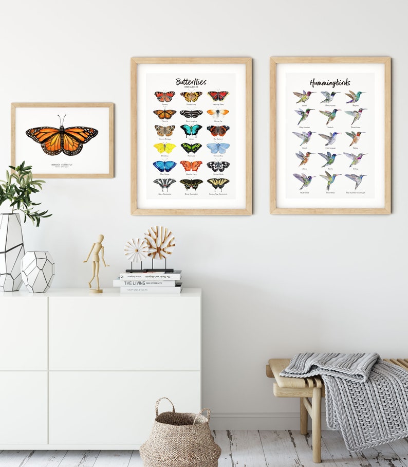 May include: Three framed prints of butterflies and hummingbirds. The prints are on a white wall with a white dresser and a wooden bench with a gray blanket. The prints are all in a light wood frame.