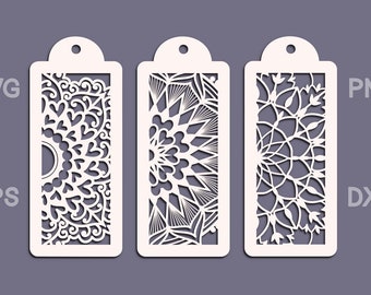Op de afbeelding: Drie witte decoratieve bladwijzers met ingewikkelde lasergesneden ontwerpen. De ontwerpen bevatten bloem- en geometrische patronen.
