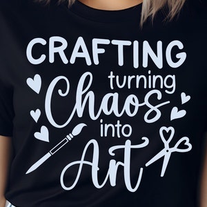 May include: Black t-shirt with white text that reads "Crafting turning Chaos into Art" with a paintbrush and scissors graphic.