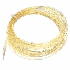 Puede incluir: Una bobina de alambre de color dorado. El alambre está enrollado en círculo y tiene un diámetro de aproximadamente 6 mm.